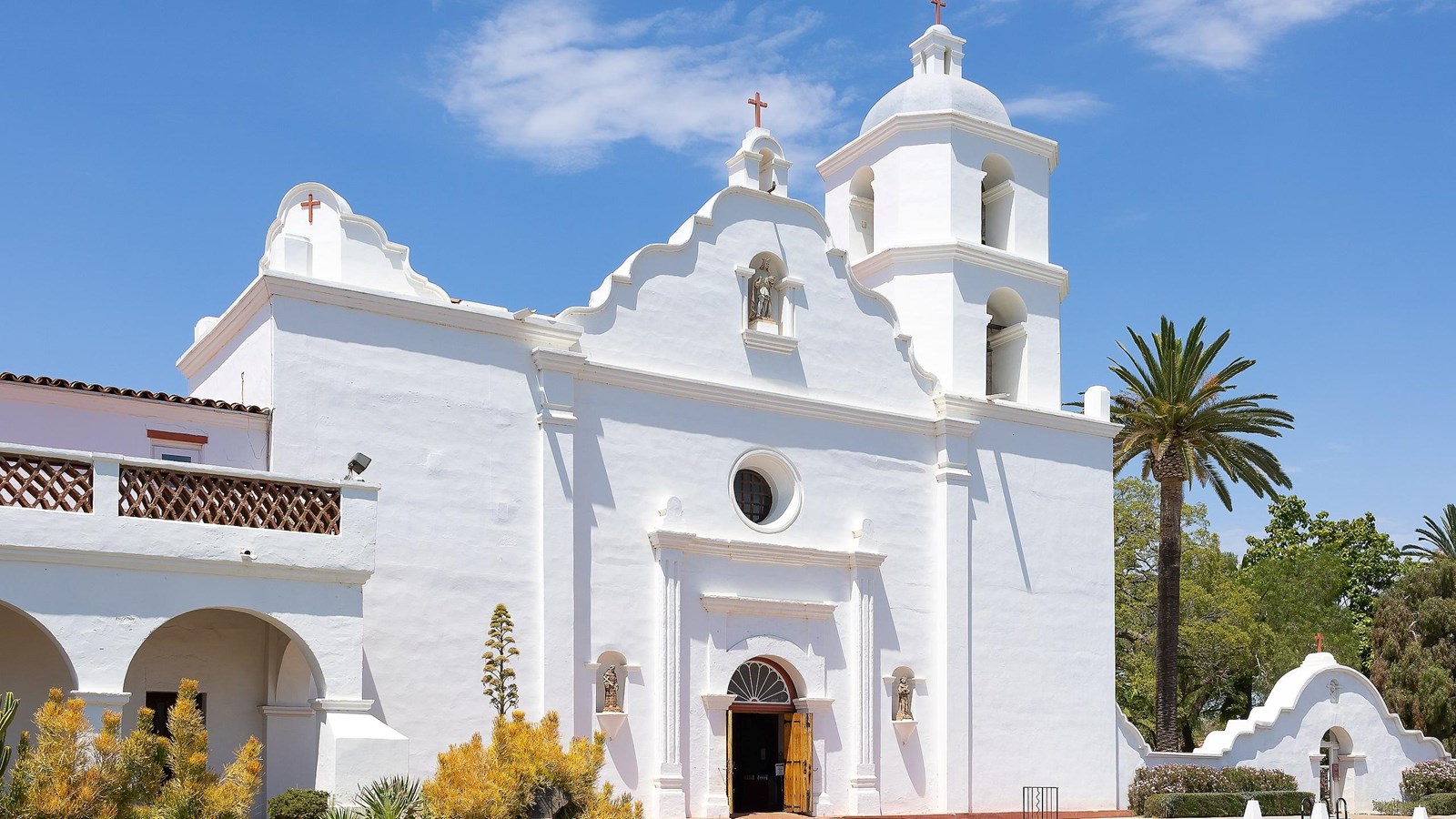 Bright white building with circle window over door and tower with 4 windows to the right.