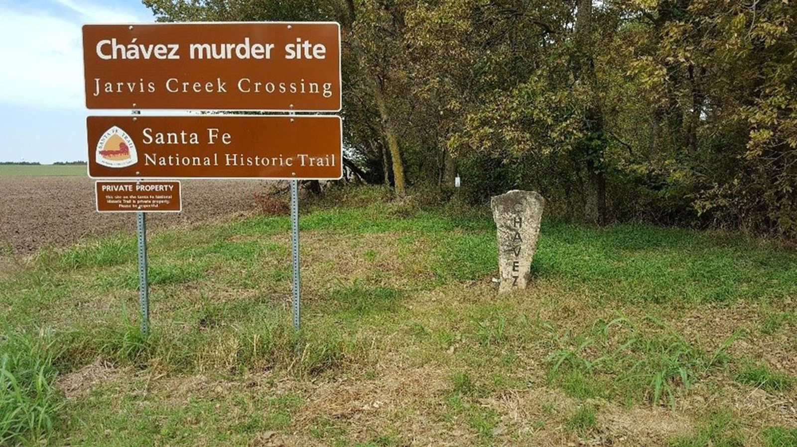 Stone marker and metal sign in a grassy pasture