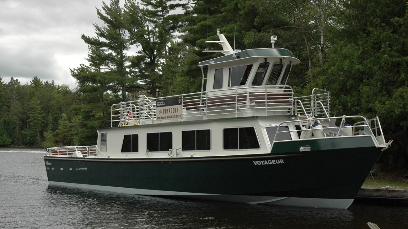 The park tour boat docked at Kettle Falls with trees in the background