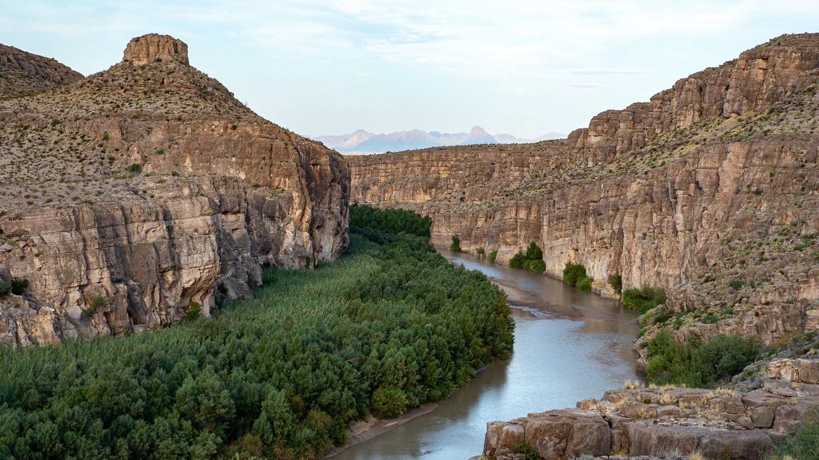 A wide river curves through a canyon with high limestone walls.