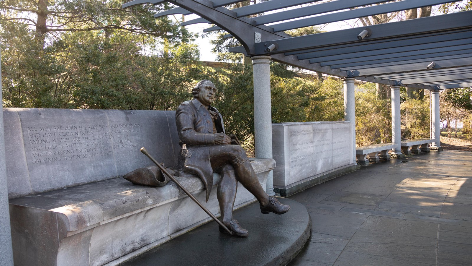 A statue of George Mason as he sits with a book in his hand looking out into the distance. 