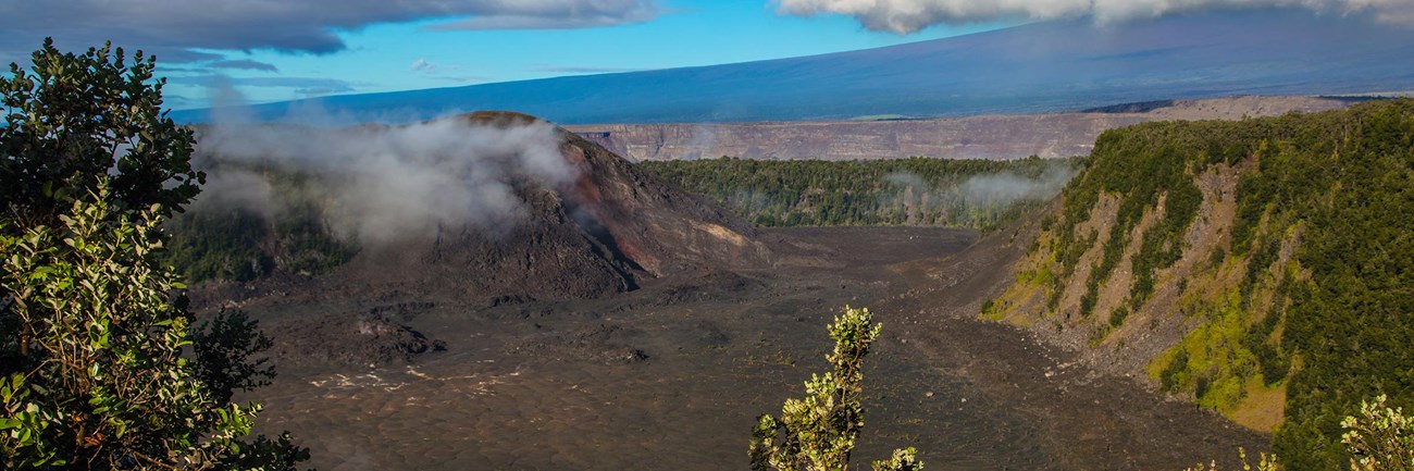 Volcanic crater with a large cinder cone on the left-hand side and a larger mountain beyond.
