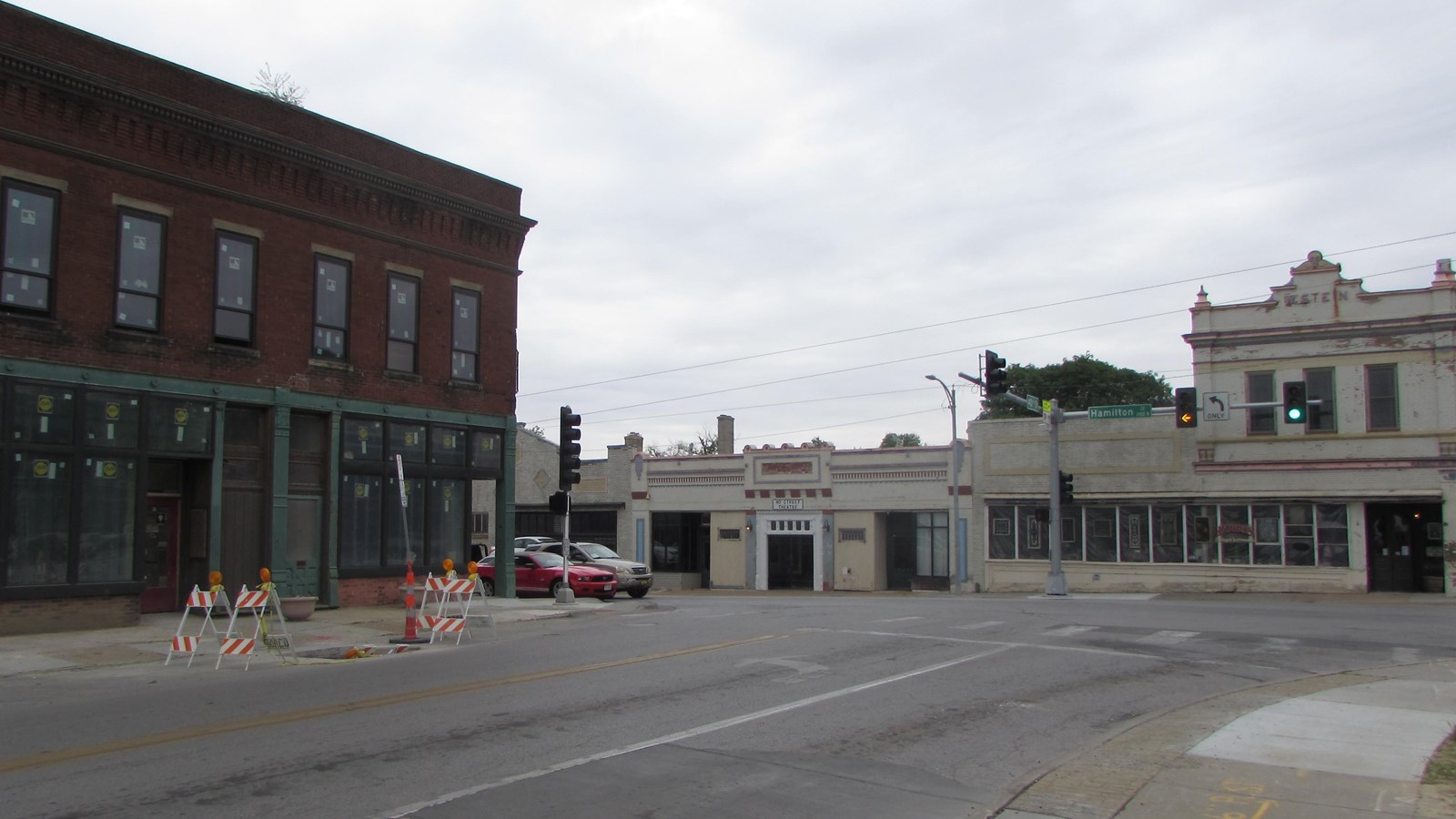 Two-story brick commercial building  at corner with one-story commercial buildings opposite.