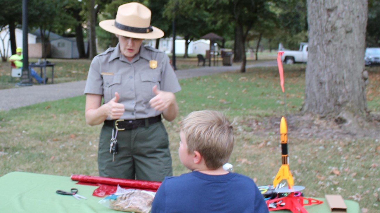 Female ranger talking to a young boy with a table between them