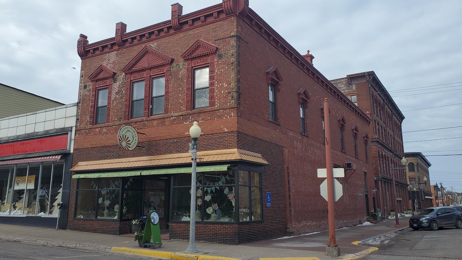 Two story red brick building. Sign above the door reads “Calumet Floral & Gifts.”