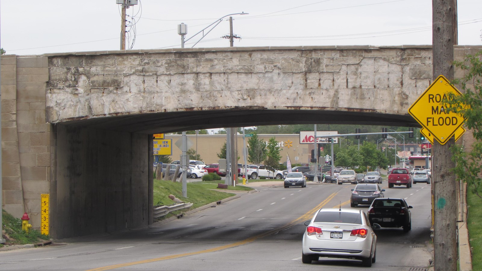 Concrete overpass spanning three lane traffic. Concrete sidewalls and abutment.