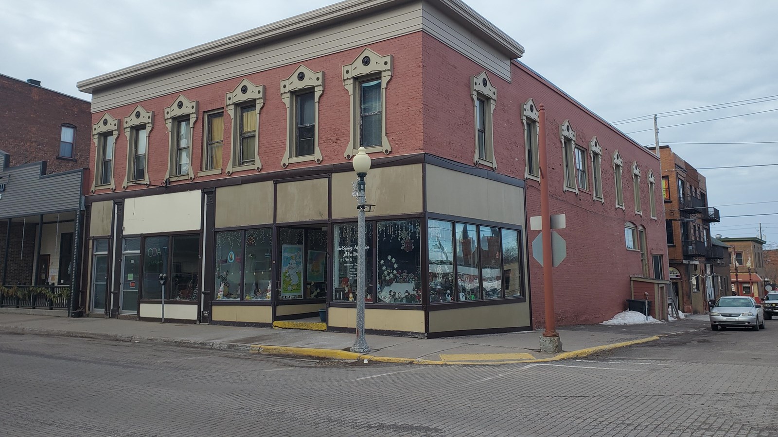 Two story red brick building with display windows on the first floor and ornate windows on the 2rd.