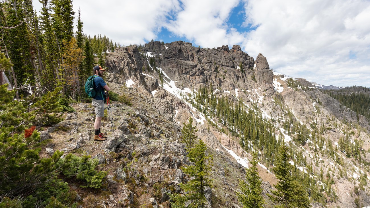 A hiker takes in the views approaching a rocky summit.