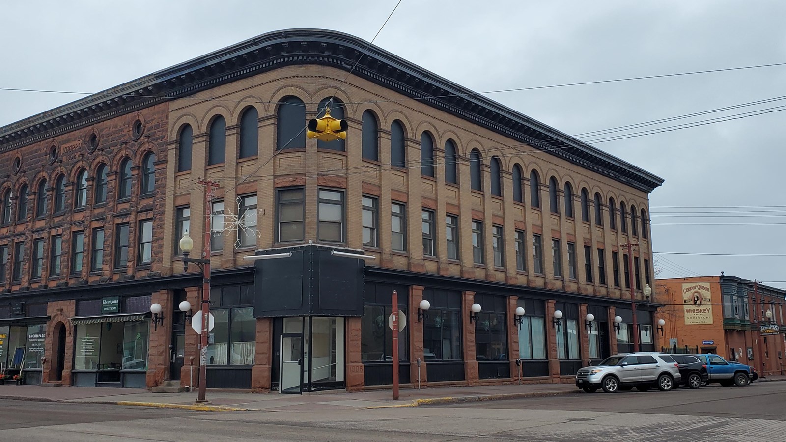 Three story red sandstone and yellow brick building with ornate cornice.