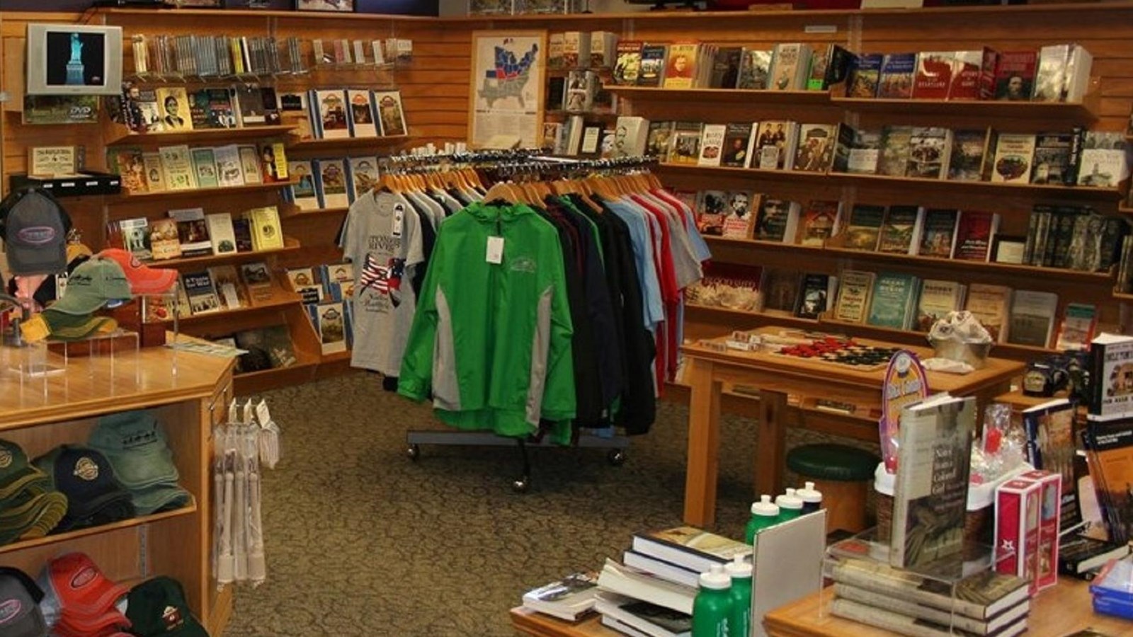 A room with shelves of books and other items. Tables and clothing racks in the middle.