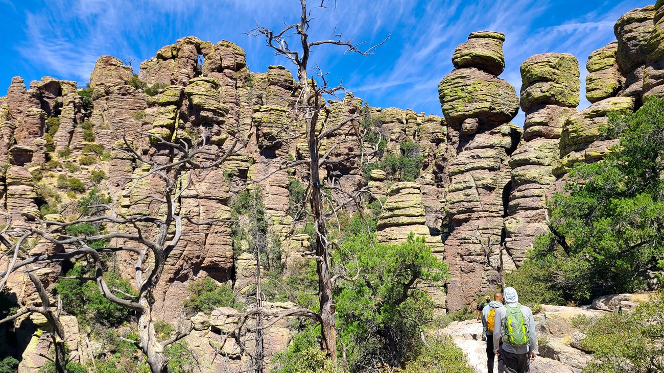 Hikers in front of pillar rock formations with a blue sky