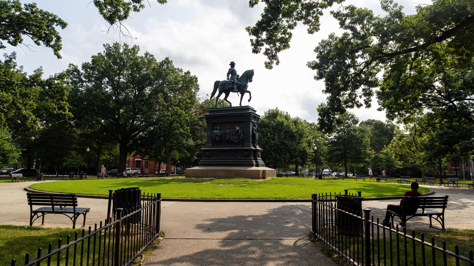 A circular park with a statue of a man on a horse in the middle