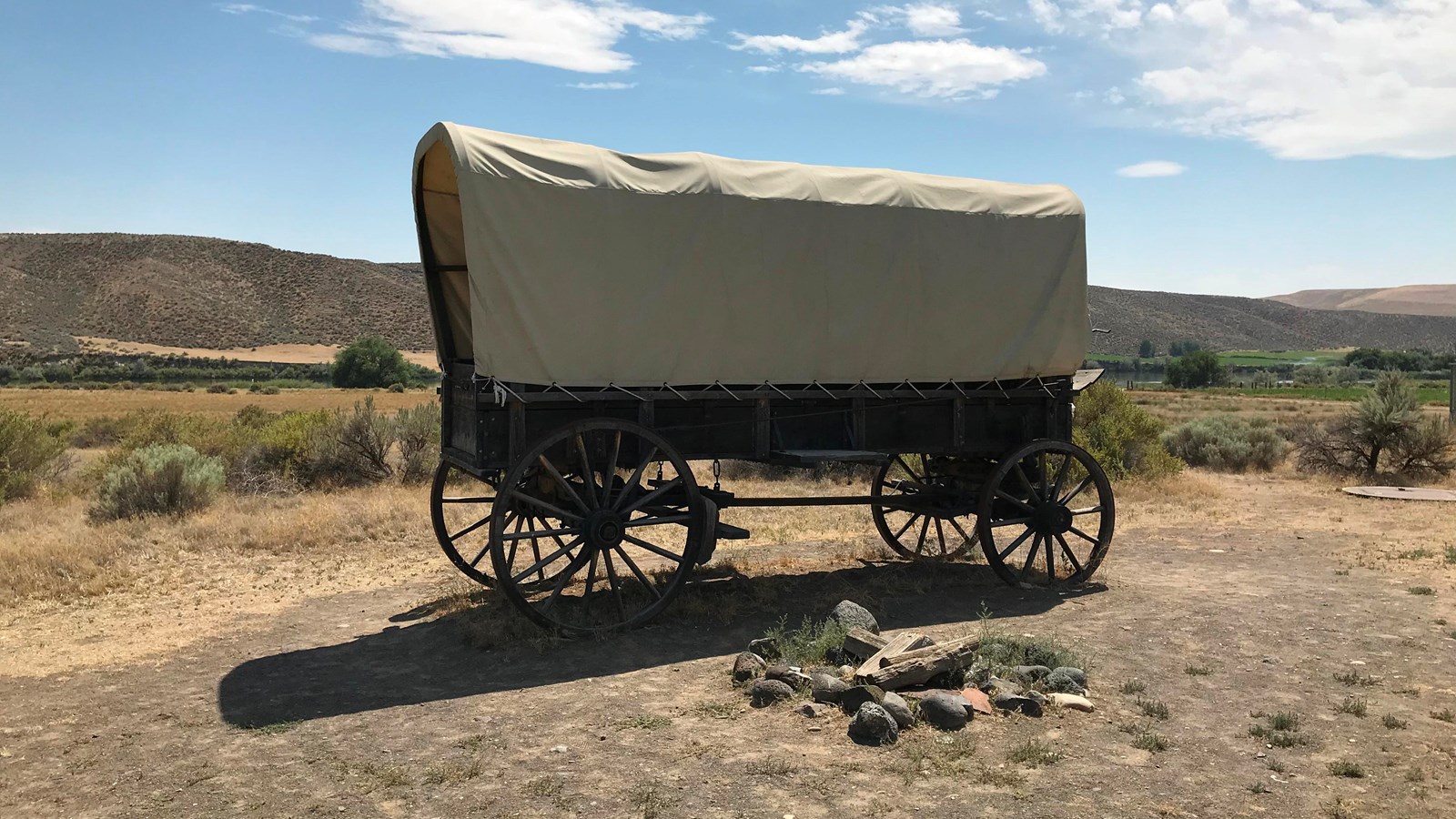 A covered wagon sits in a desert setting.