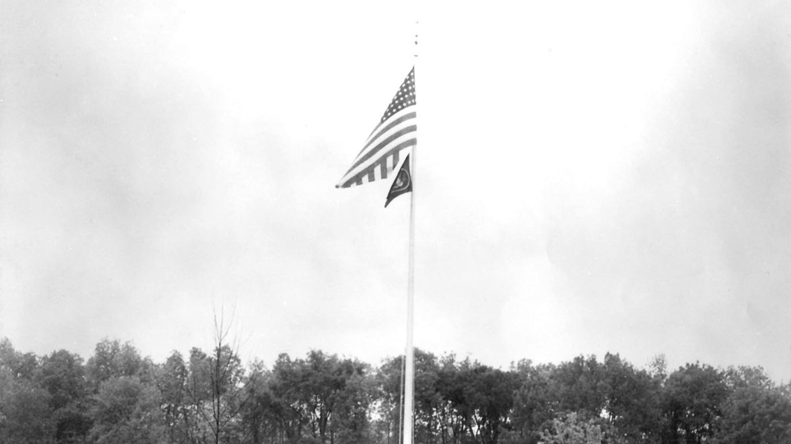 The American flag flies above the Presidential flag on a tall flag pole.