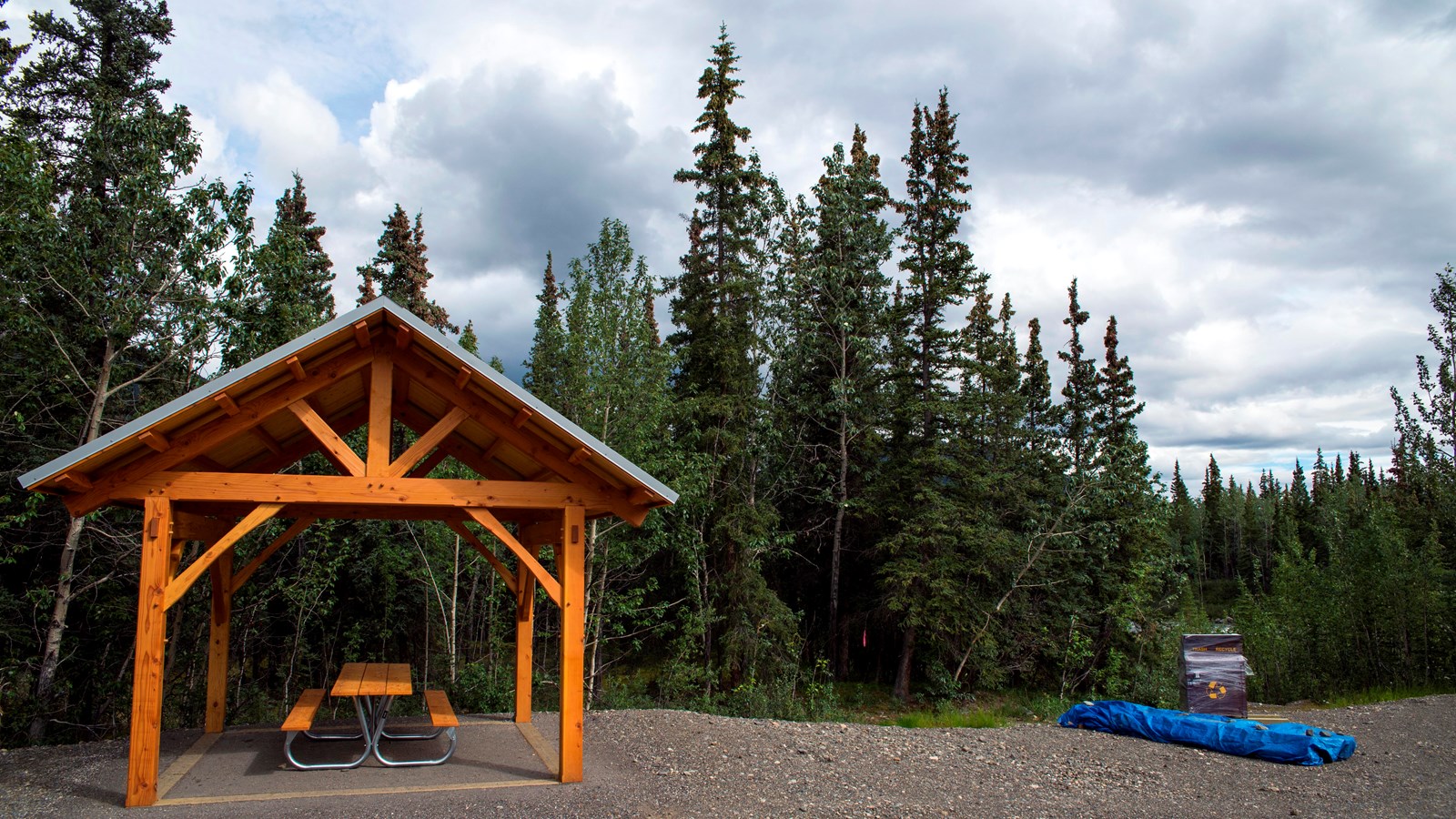 a large shelter covering several picnic tables near spruce trees