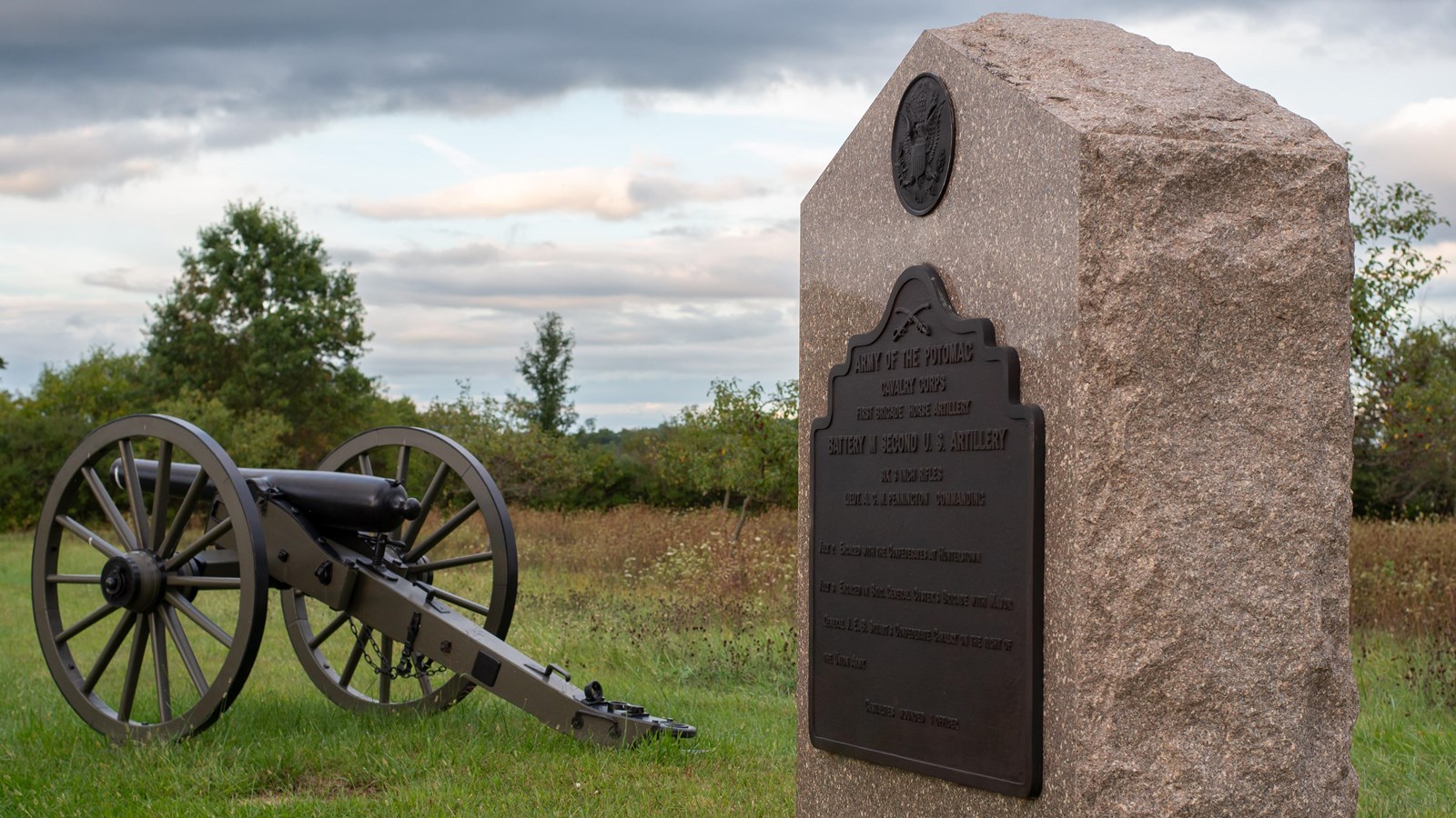 A stone monument next to a cannon along a tour road