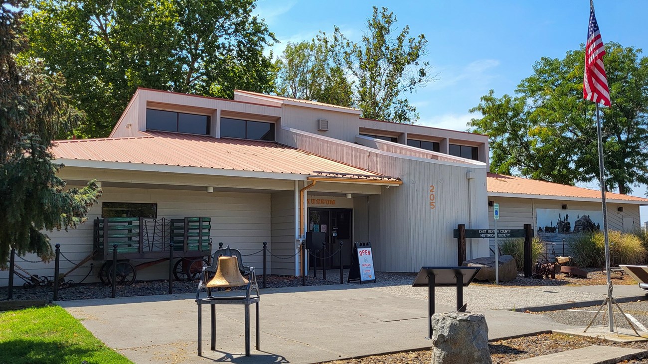 Color photograph of a wooden building with the word ‘Museum’ on its glass entrance doors.