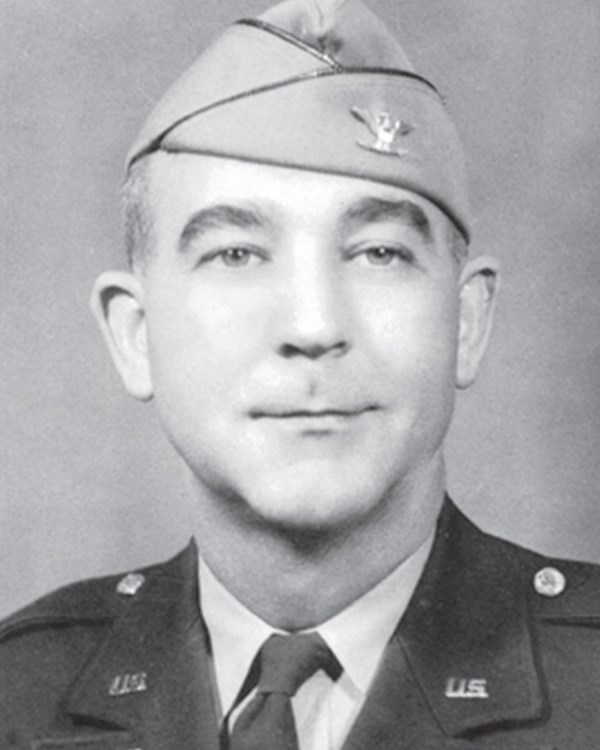 Middle aged man wearing a uniform hat and suit with military insignia noting his rank 