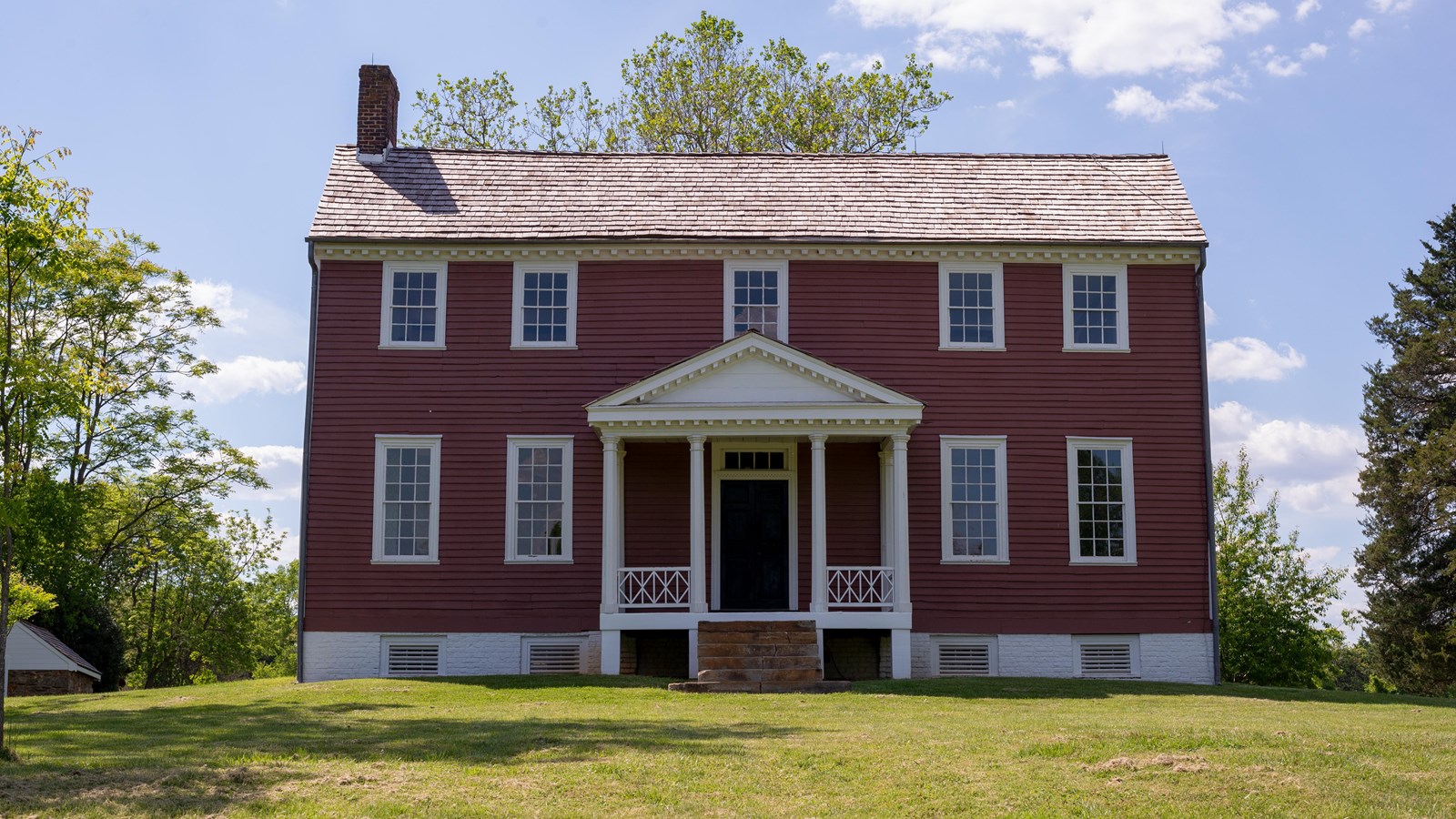 Front view of 2.5 story red farmhouse.