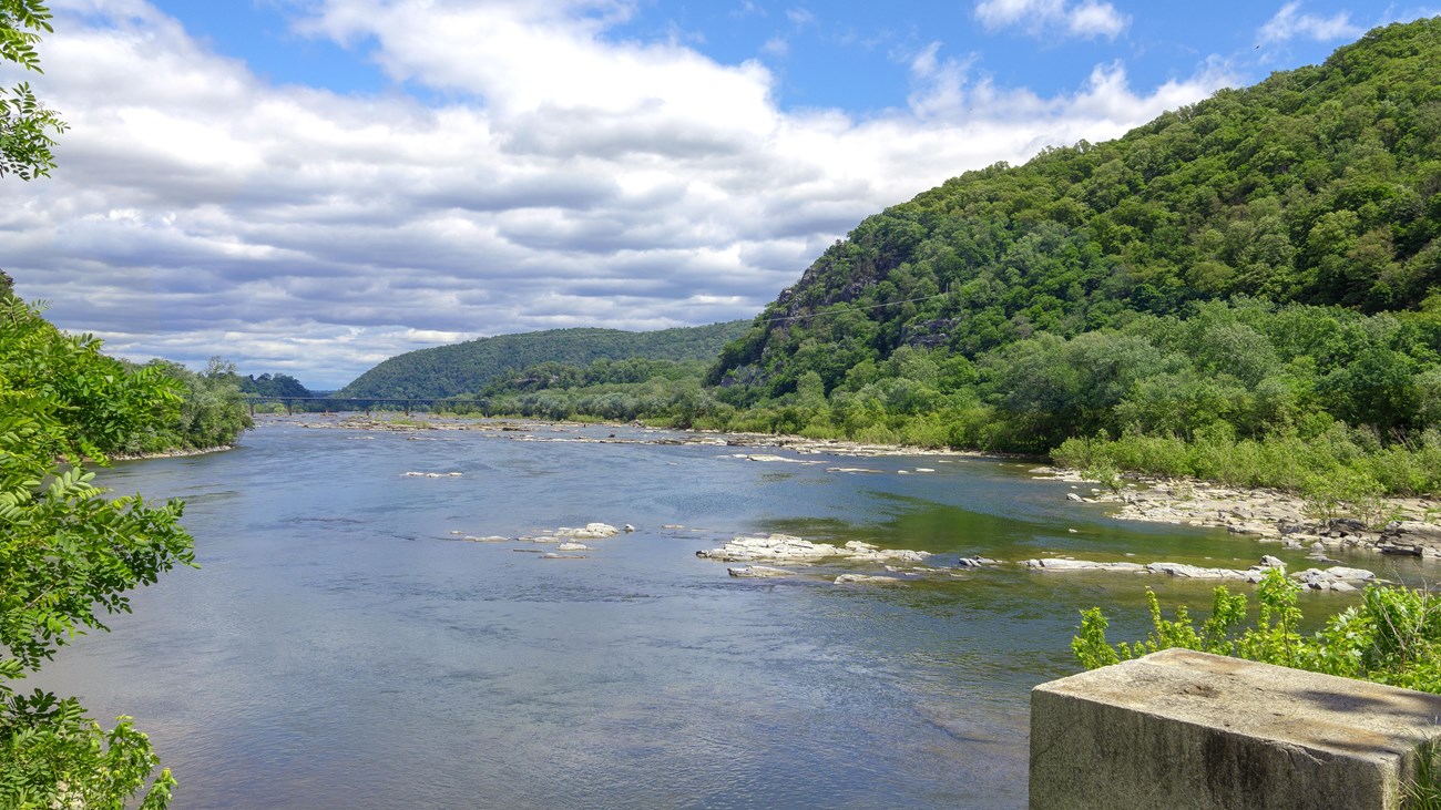 A wide blue river flows through a gap between green mountains.