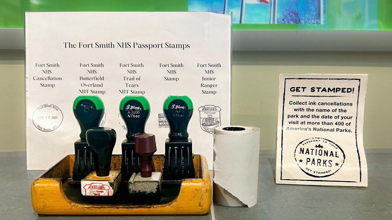 Five rubber stamps sitting at a wood stamp station in front of black ink images of each stamp.