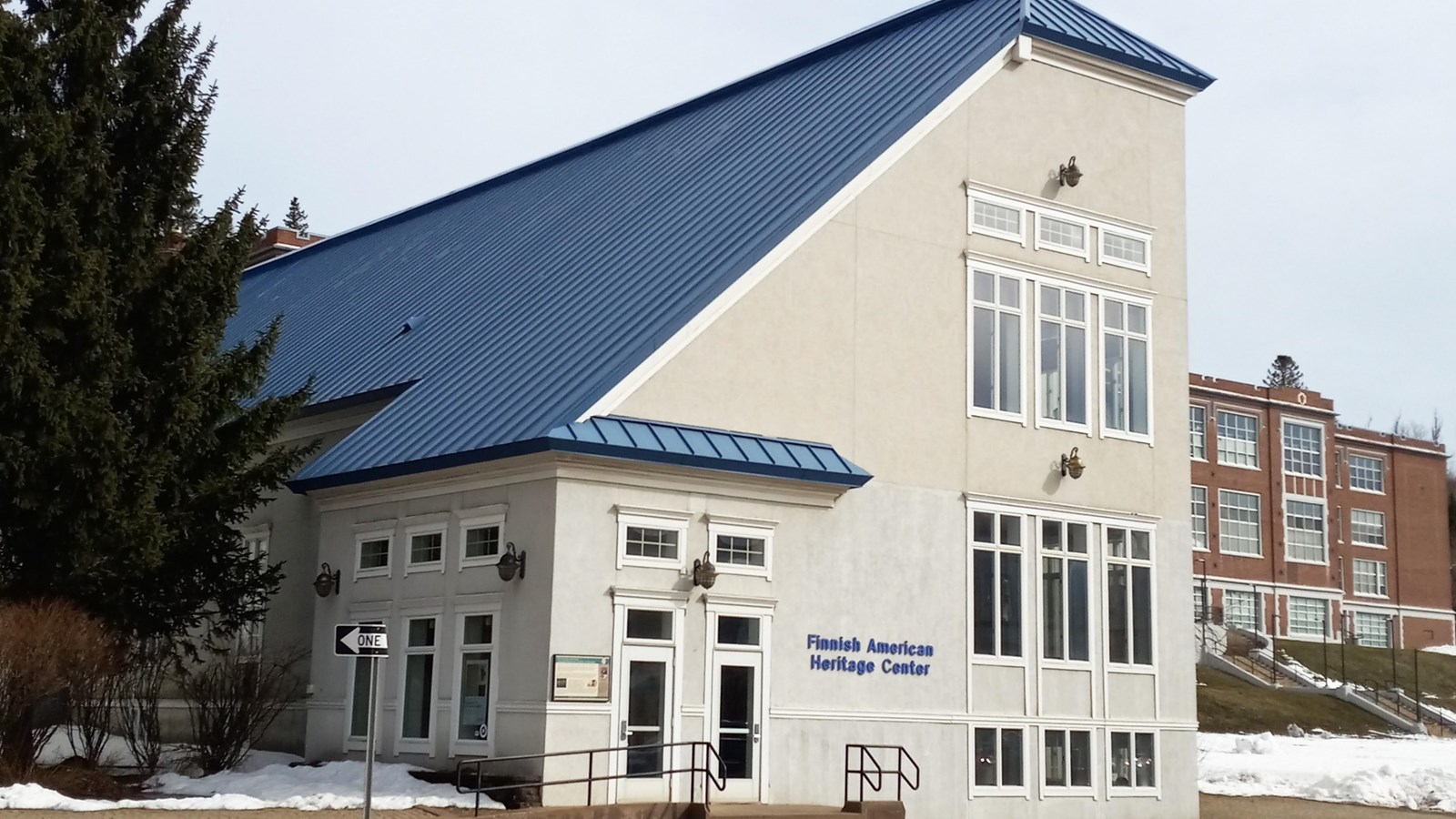 A multistory building with a white exterior and steeply-angled, blue roof. 