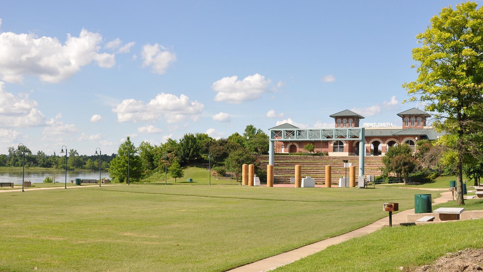 Large amphitheater grass lawn with brick event buildings in the far background.