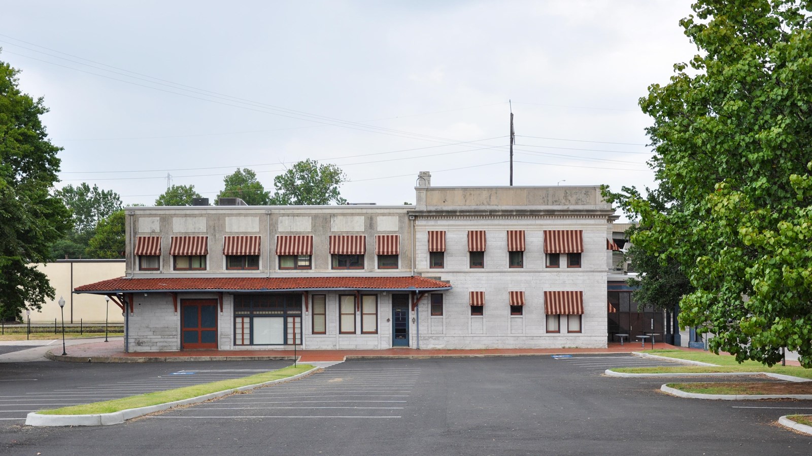 Two story white limestone structure with cotta tiled awning on the left side of the building.