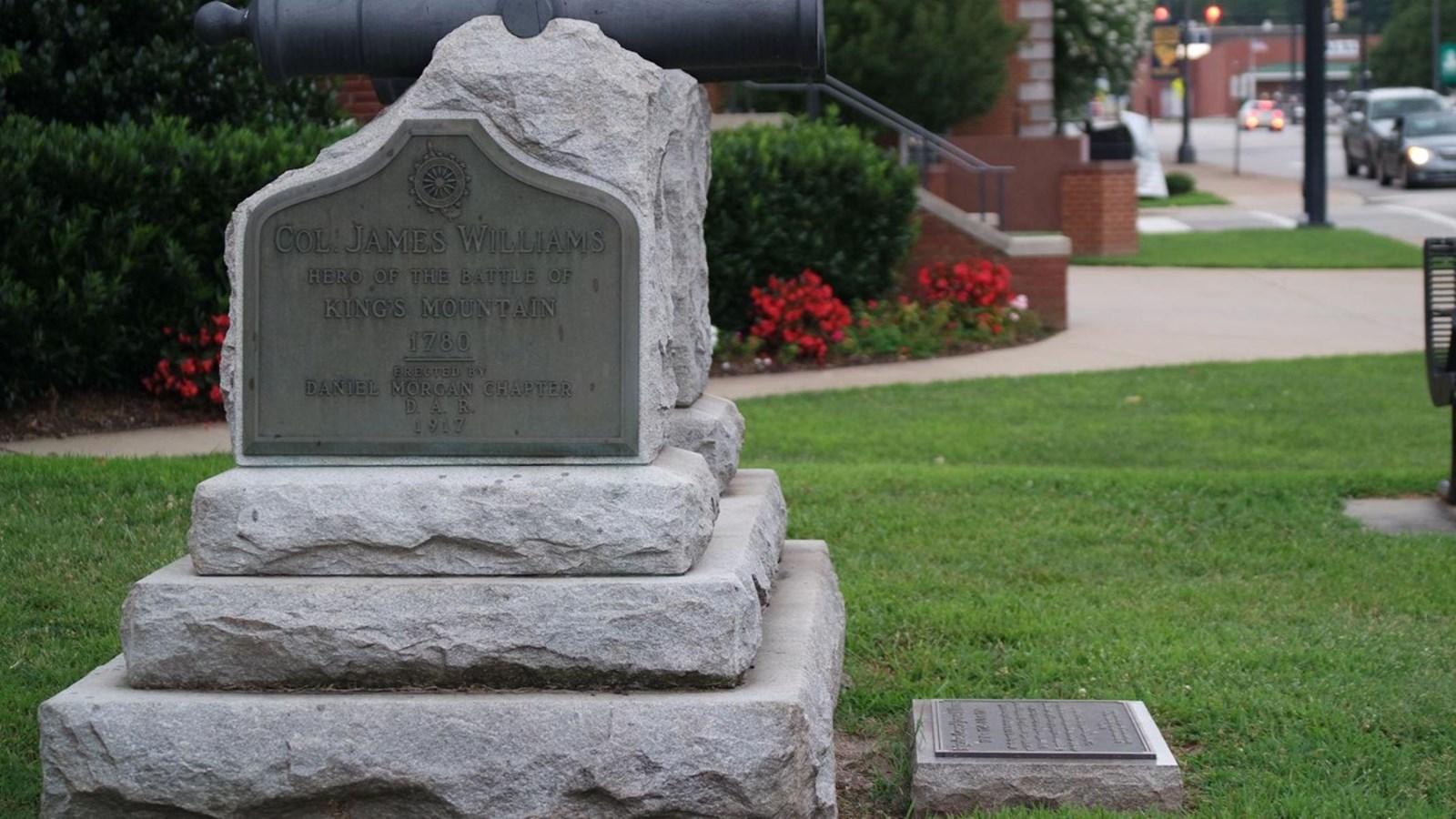 A stone with a metal plaque on it for James Williams. A cannon is attached to the top.