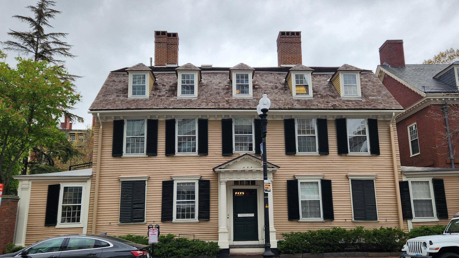 Yellow three-story house with symmetrical windows, facing directly on busy street.