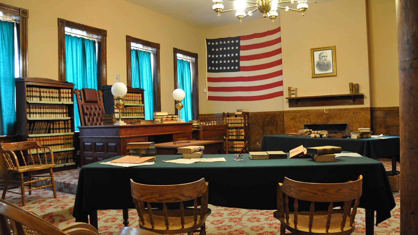 Courtroom – jury chairs on the left, two attorney tables in center and judge’s desk is center right.