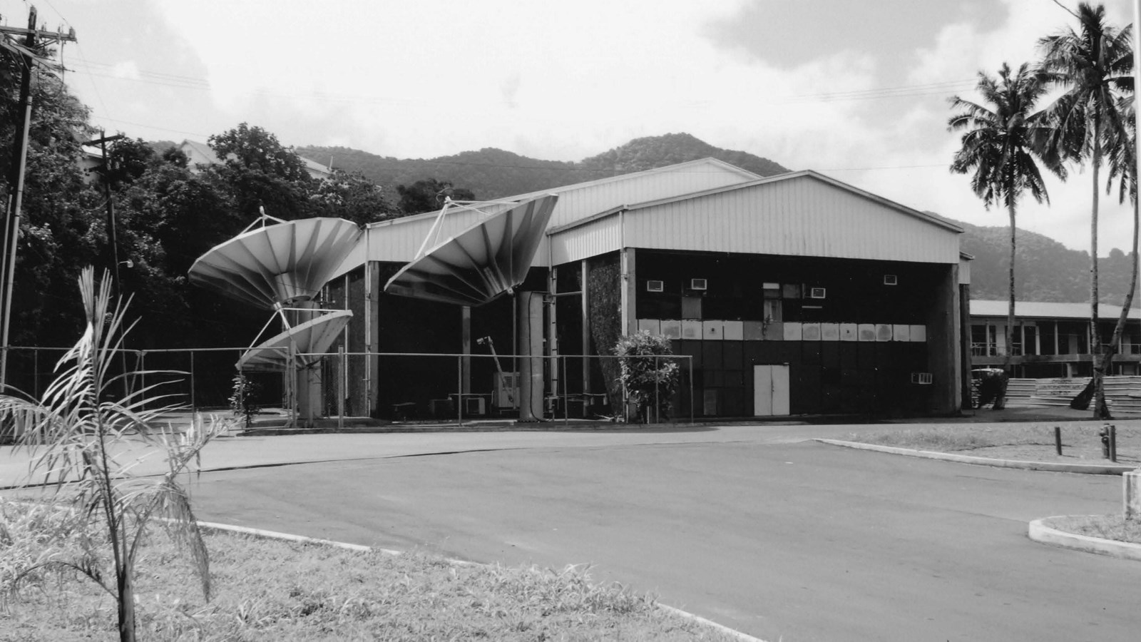 Building with two large satellite dishes, surrounded by palm trees