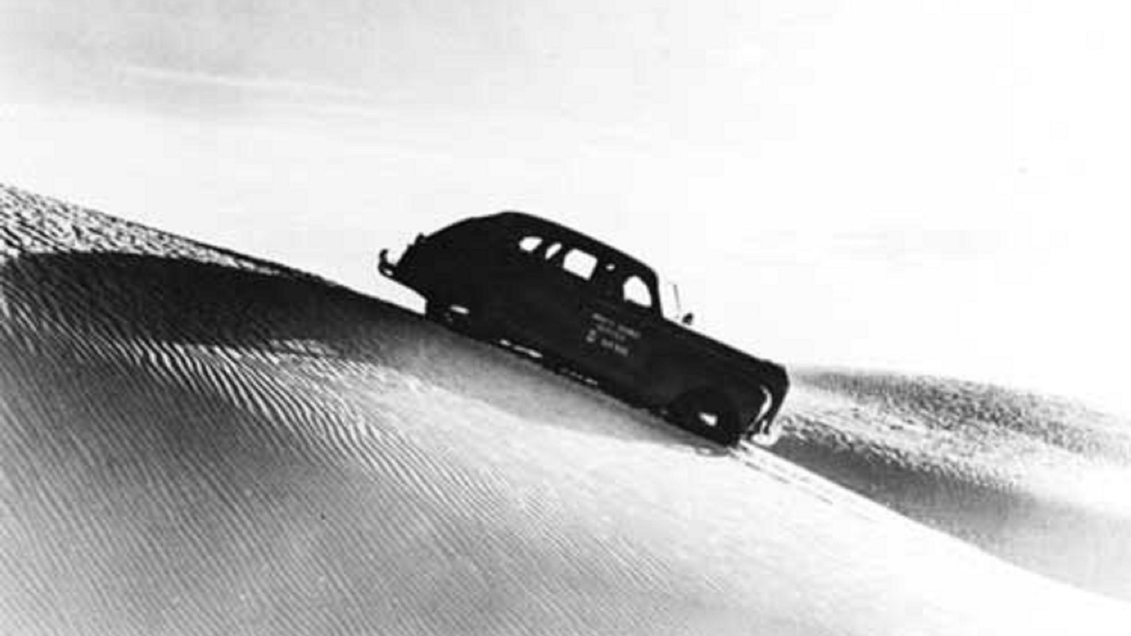 Tom Charles\' White Sands Touring Company vehicle driving in the dunefield.