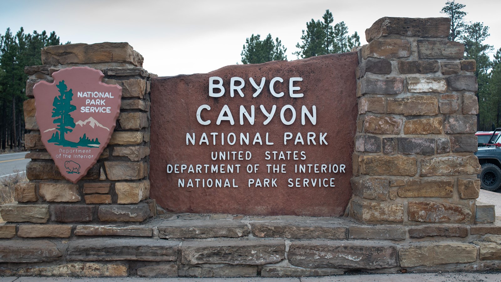 A stone monument sign of red rock reading Bryce Canyon National Park Department of the Interior