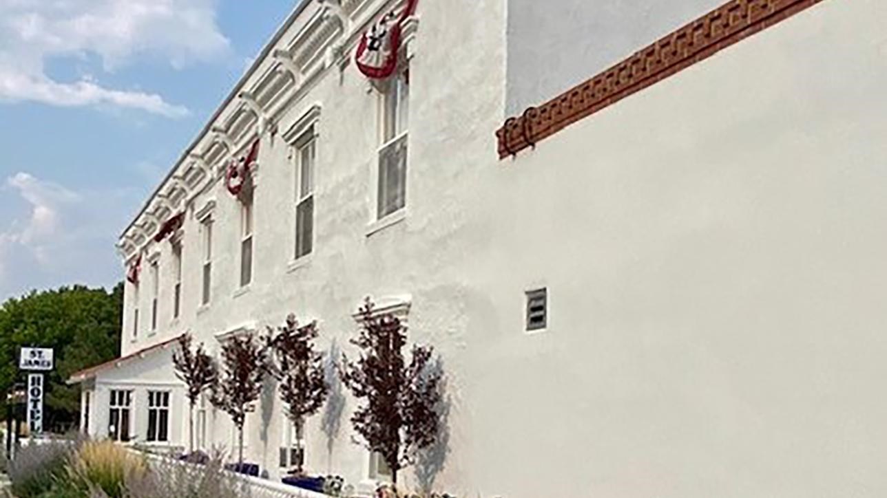 A long, white, stucco building with two levels of windows with flower boxes. 