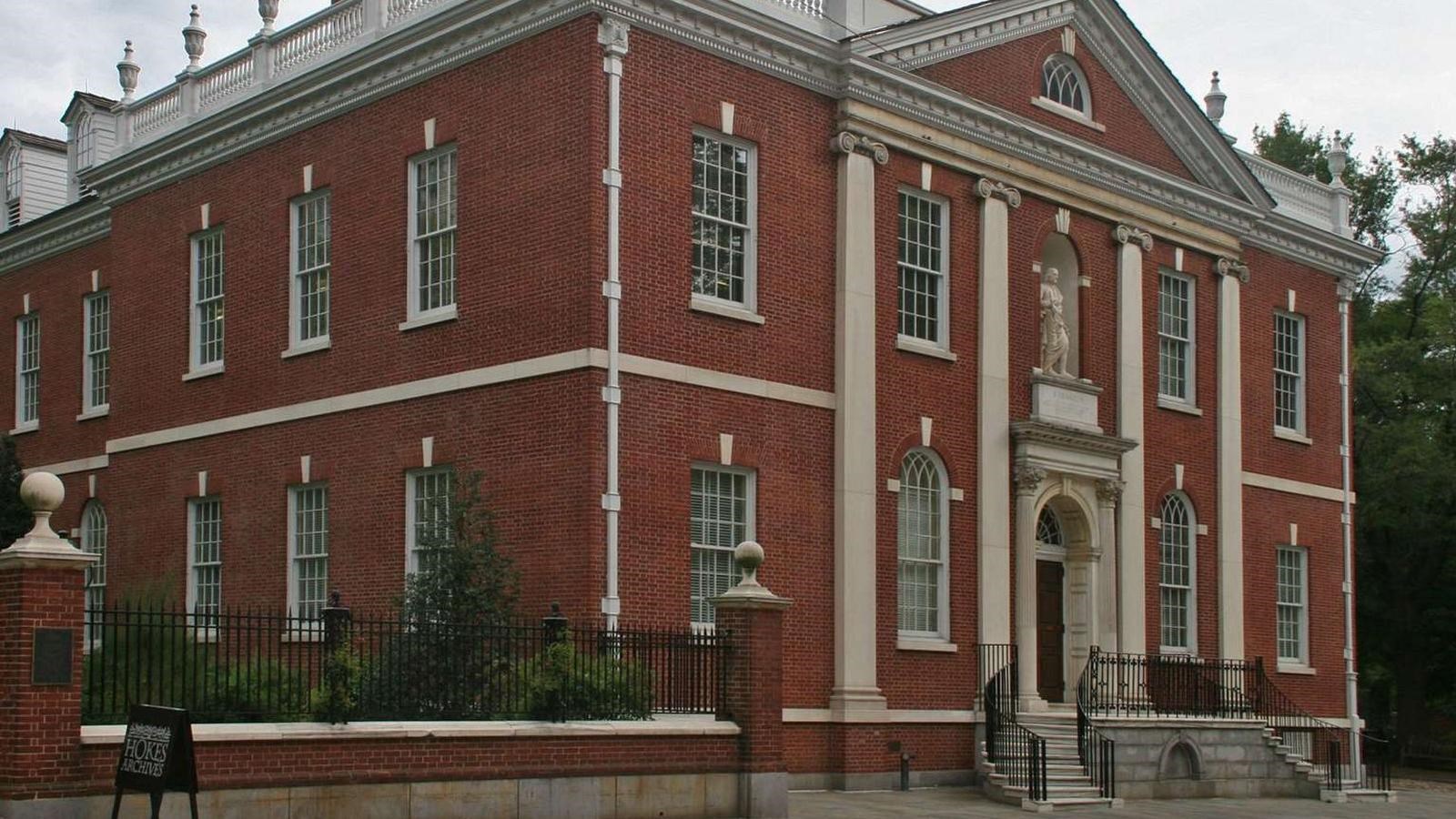 A color photo of a two story brick building with white trim and two rows of windows on each floor.
