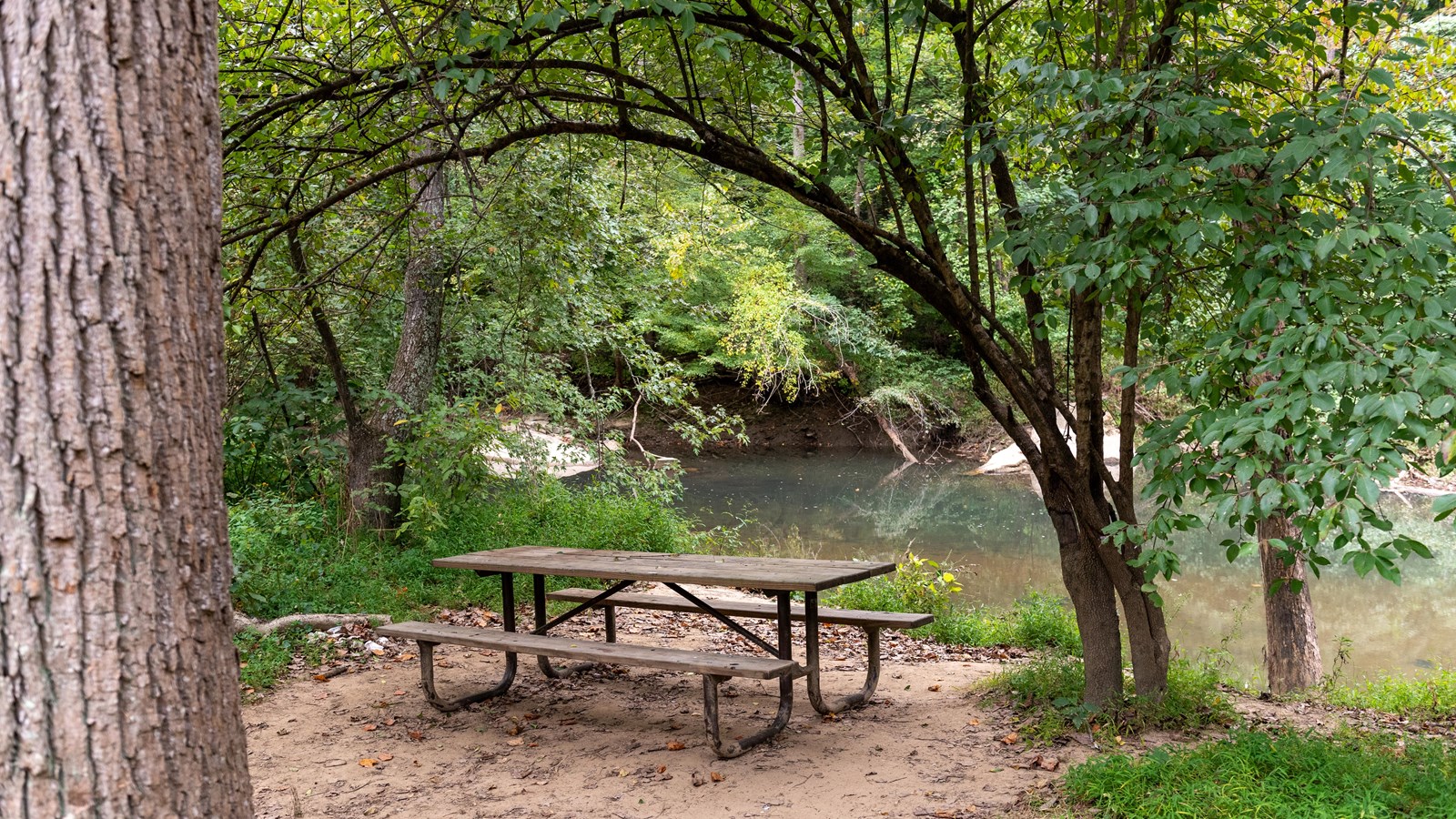 A picnic bench next to a river. 