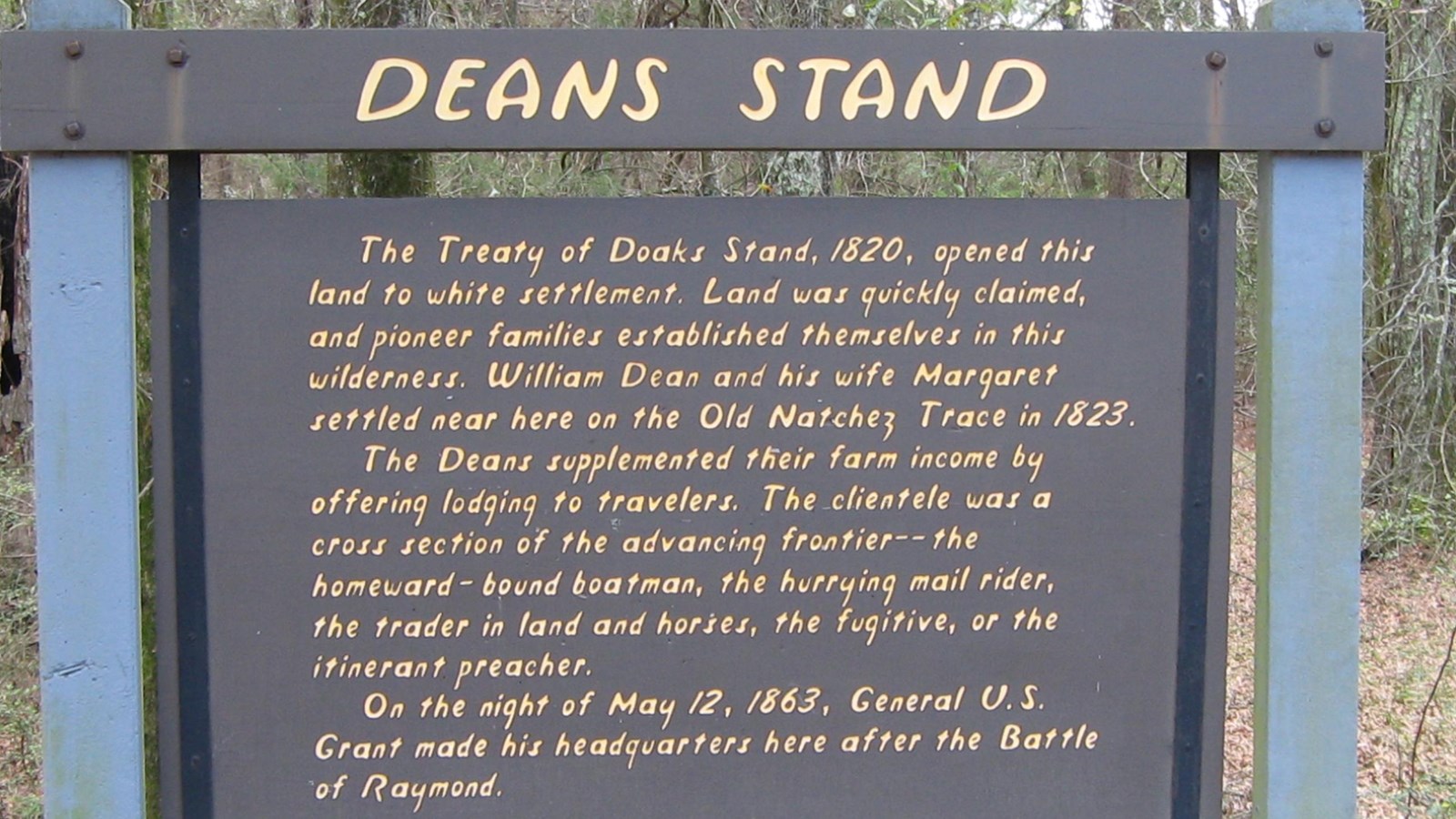 Wooden sign painted brown with yellow letters titled 