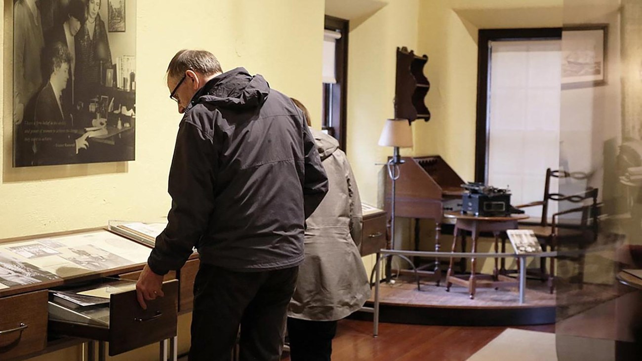 A man and woman open a drawer to see artifacts displayed inside.