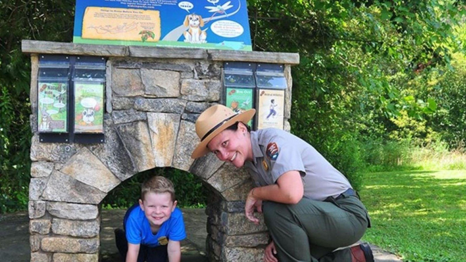 Ranger and small boy in front of stone monument