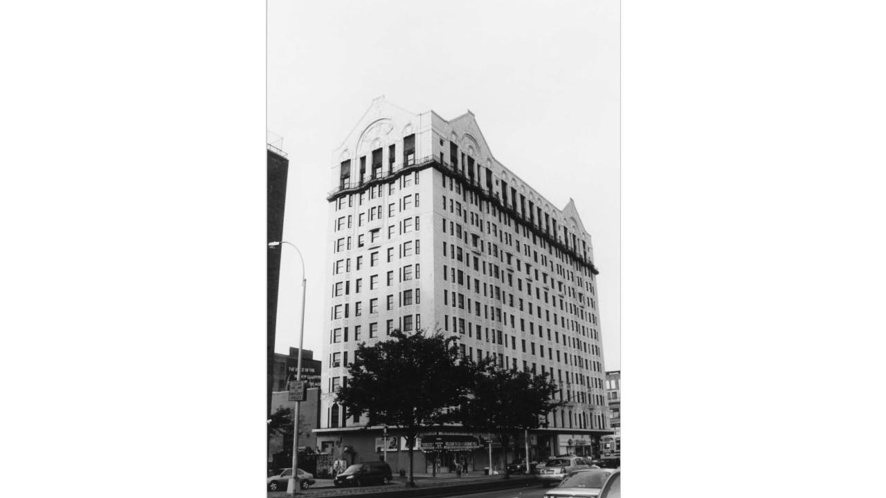 13 story hotel building with two trees in front of the entrance and cars on the city block