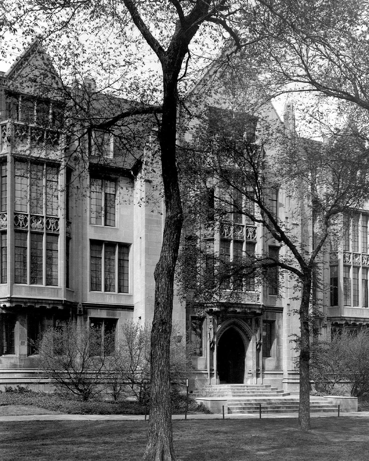 A black and white photo of a 4-story building with many windows and a large main door.