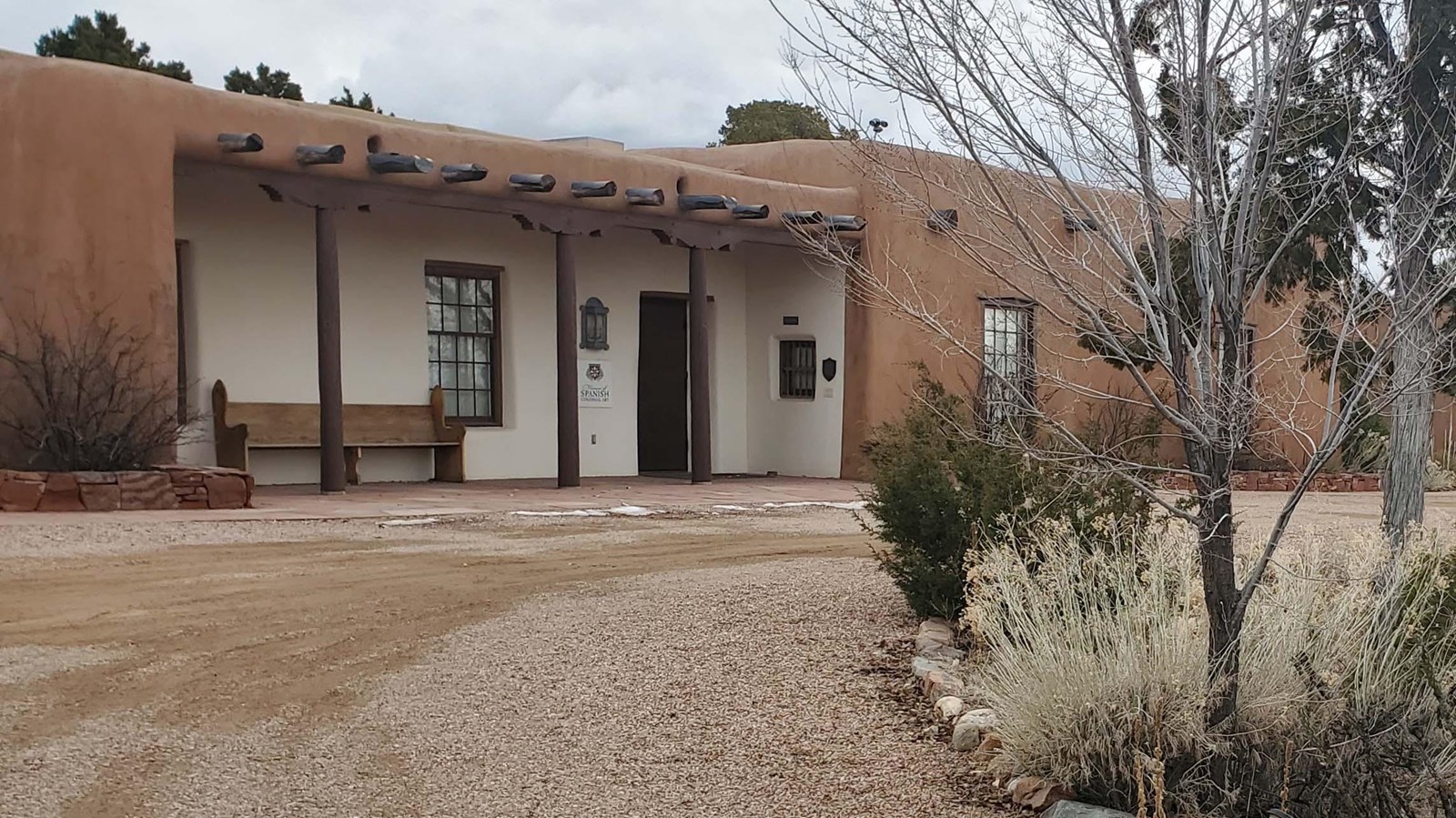 Brown and white pueblo style building along gravel drive