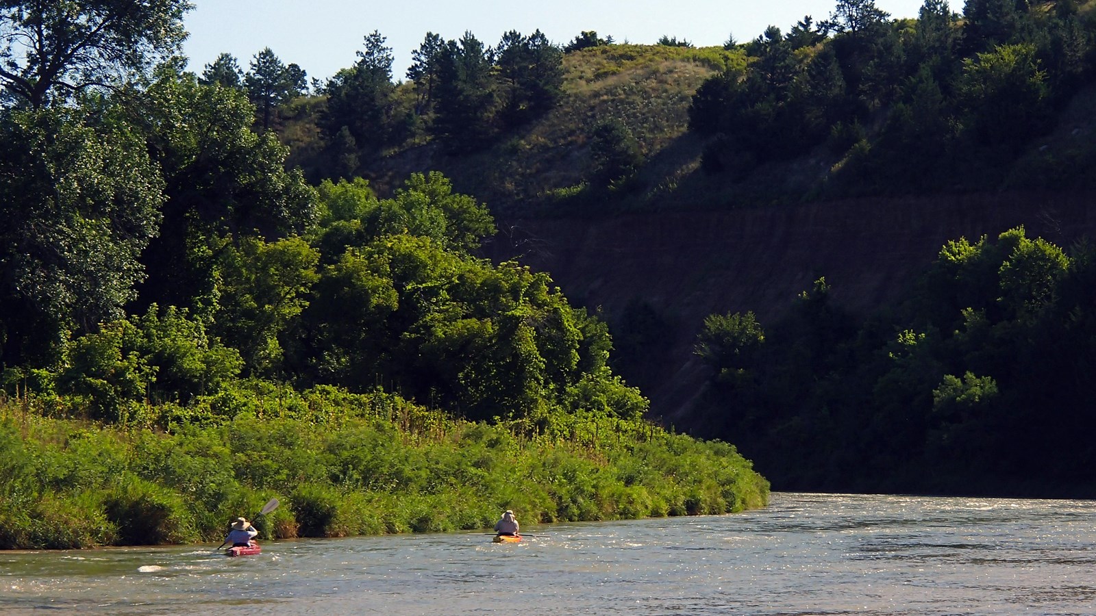 A wide river flows almost so gently around a bend, the water runs smooth.