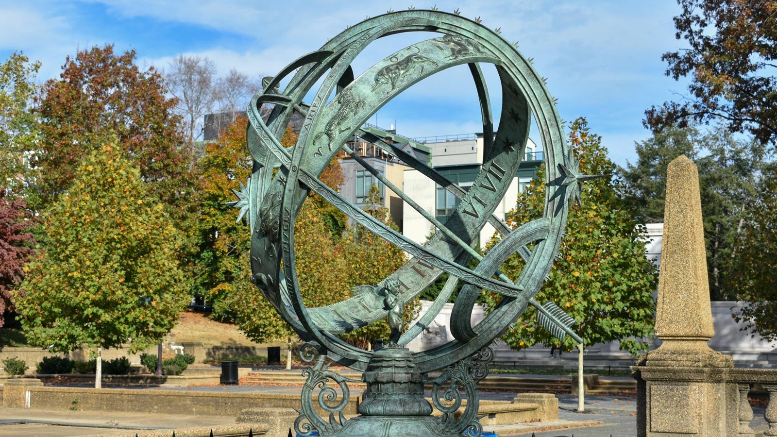 A newly installed weathered copper Armillary Sphere sculpture at Meridian Hill with fall trees.