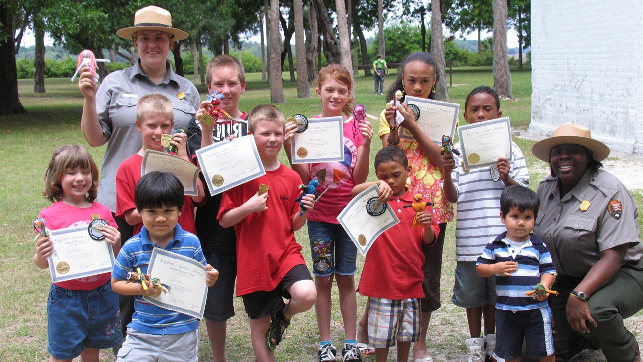 two ranger on either side of group of kids holding certificates