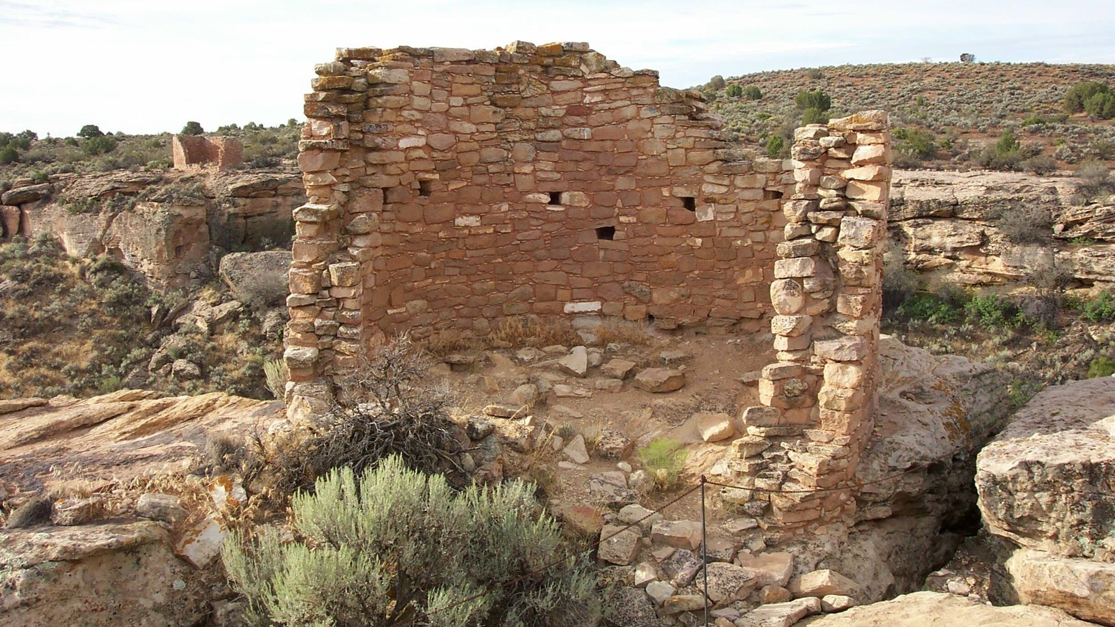 A half-circle remains of a circular stone tower, perched on the cliff edge.