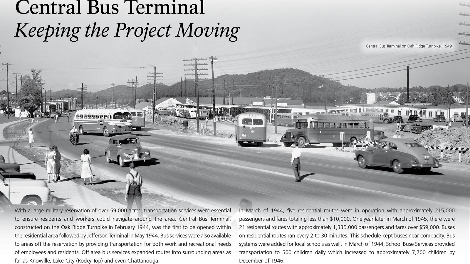 A wayside with text and a photo of several buses and cars at a bus terminal.