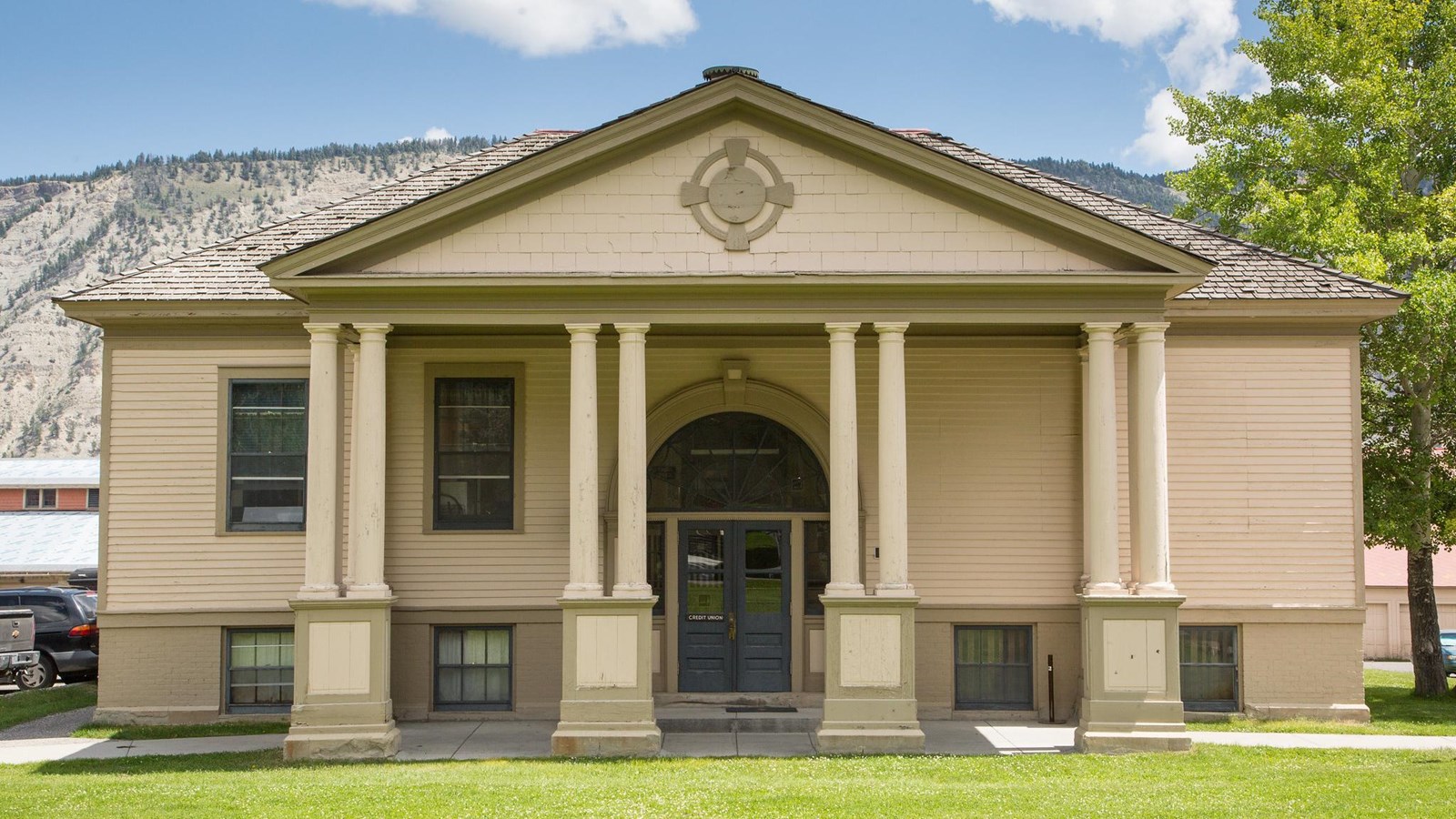 A historic building with off white siding and a porch with columns.