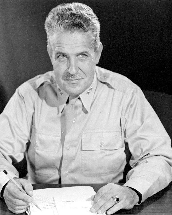 A black and white photo of a man in uniform seated at a desk.